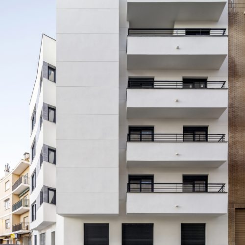 Fachada blanca con terrazas de un edificio plurifamiliar en Requena proyectado por arquitecto Valencia