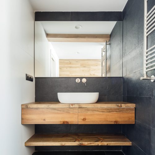 Lavabo sobre encimera y mueble suspendido de madera en baño reformado por arquitecto interiorista en Valencia