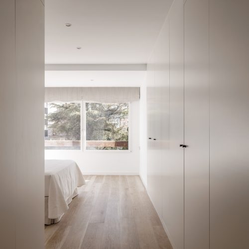 Distribuidor con armarios empotrados y luz natural hacia dormitorio en reforma integral por arquitectos Valencia