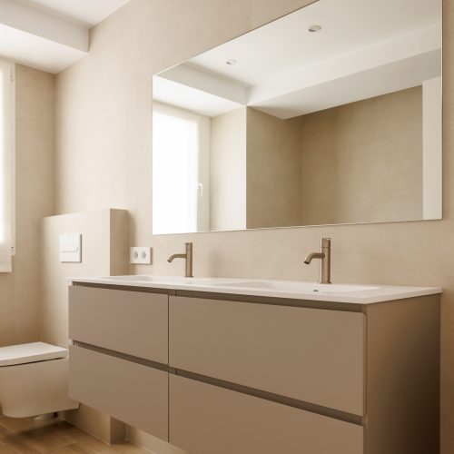 Baño principal con mueble suspendido y doble lavabo en reforma integral por arquitecto en Valencia