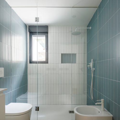 Rehabilitación energética con baño completo en suite, ducha continua, grifería blanca y cerámica vertical bicolor en Villa Muntanya