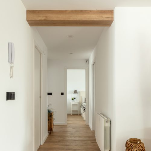 Pasillo interior con pavimento continuo y acceso a dormitorios reformado por arquitecto Valencia