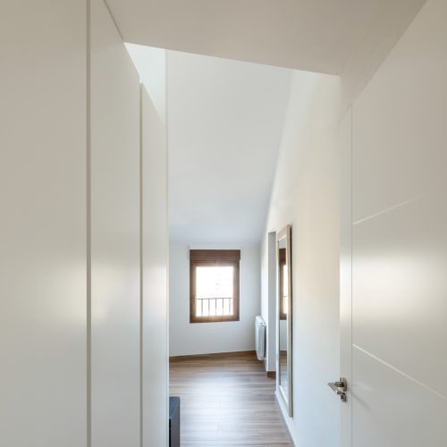 Distribuidor superior con armarios empotrados blancos y luz natural filtrada, proyectos de arquitectura residencial en Valencia