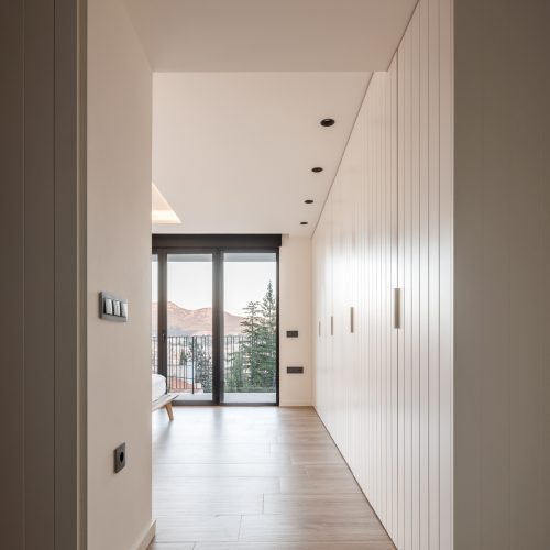 Arquitecto Valencia diseña dormitorio con armario panelado, pavimento continuo y apertura total al paisaje en vivienda unifamiliar Villa Muntanya
