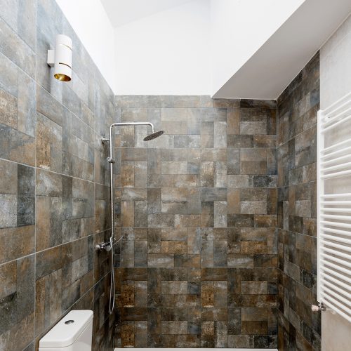 Ducha empotrada con revestimiento cerámico y luz cenital en baño de arquitecto obra nueva Valencia
