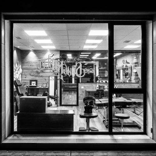 Vista exterior nocturna del estudio de tatuaje con interior visible, diseñado por los mejores arquitectos en Valencia