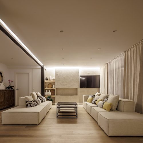 Vista frontal del salón en vivienda moderna diseñada por arquitectos Valencia, con iluminación indirecta