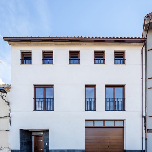 Fachada simétrica de vivienda unifamiliar entre medianeras con zócalo de piedra, arquitectos Valencia