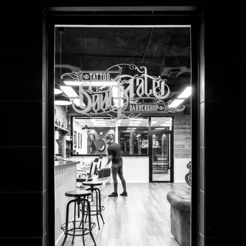 Vista interior desde escaparate nocturno de barbershop diseñada por arquitecto en Valencia