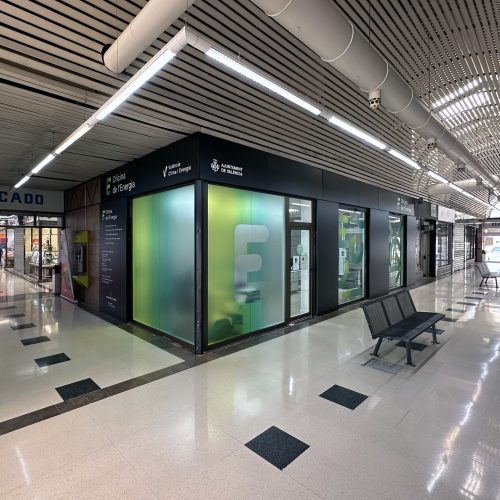 Fachada acristalada de la Oficina de la Energía en Torrefiel, intervención desarrollada por arquitecto Valencia en entorno de mercado cubierto.