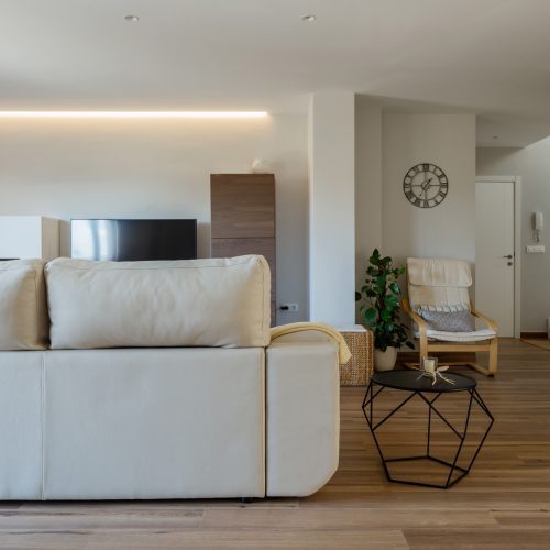 Salón diáfano con luz natural, mobiliario neutro y revestimientos cálidos, estudio de arquitectura en Valencia