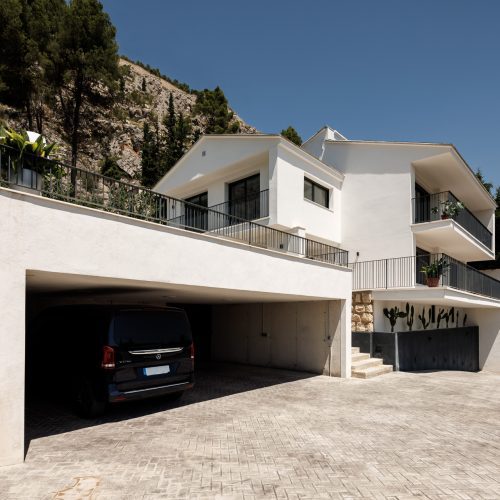 Arquitectura unifamiliar con garaje semi-enterrado, plataforma superior ajardinada y acceso en pendiente en Villa Muntanya