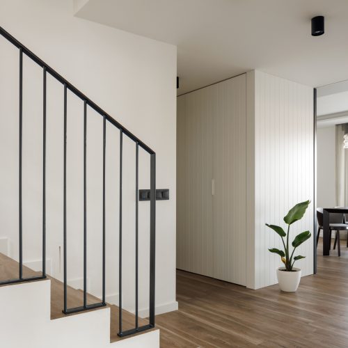 nteriorismo residencial con escalera blanca, barandilla metálica y revestimiento vertical en distribuidor de vivienda reformada en Villa Muntanya