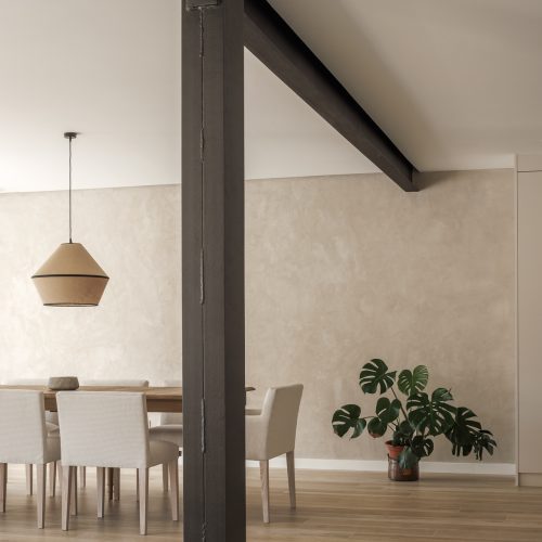 Comedor con estructura metálica expuesta y acabados sobrios en reforma por arquitectos Valencia