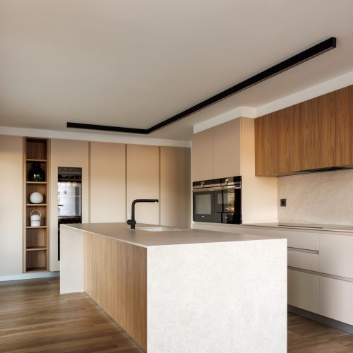 Diseño de interiores con isla central en cocina abierta, encimera mineral y mobiliario integrado en vivienda unifamiliar de Villa Muntanya