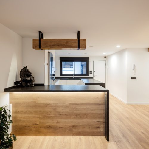 Cocina interior reformada con encimera negra y madera natural diseñada por arquitecto de calidad Valencia