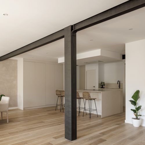 Espacio abierto con estructura metálica y cocina integrada en reforma por arquitectos Valencia