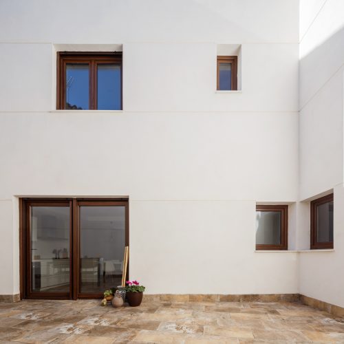 Patio interior con huecos asimétricos, cerramiento blanco y carpinterías de madera, arquitecto de calidad Valencia
