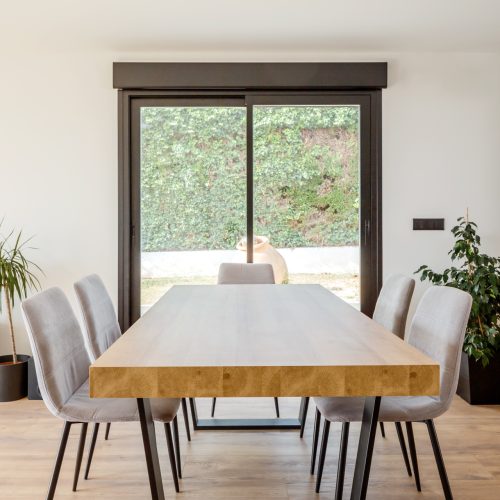 Comedor interior con mesa de madera maciza y luz natural en proyectos de arquitectura residencial en Valencia