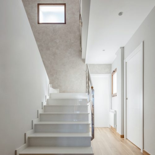 Escalera interior blanca con luz cenital y pavimento de madera, proyectos de arquitectura residencial en Valencia