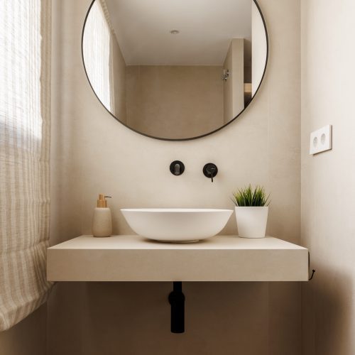 Lavabo sobre encimera volada en baño con revestimiento continuo por arquitecto en Valencia