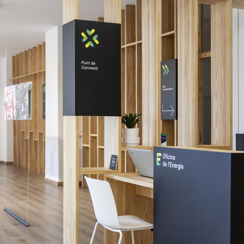 Módulo de atención al público con paneles de madera diseñado por arquitectos Valencia en un espacio de reforma energética.