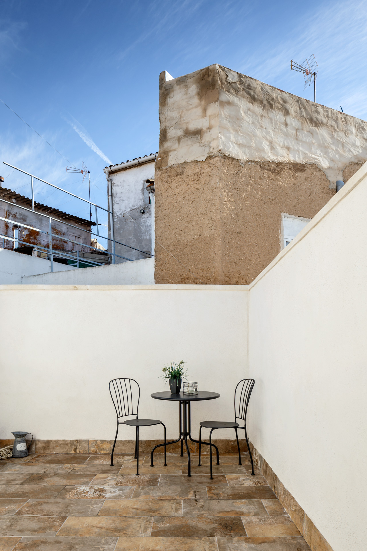 Espacio exterior en patio privado con mobiliario metálico y muros medianeros, proyectado por arquitecto en Valencia.