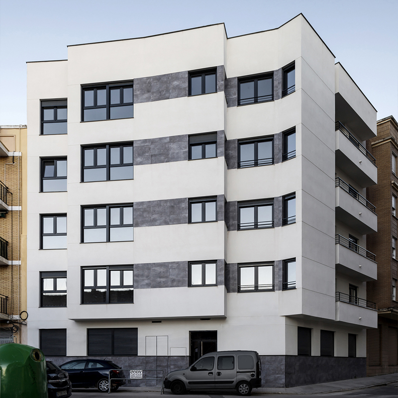 Fachada con bandas cerámicas grises y ventanas negras en edificio proyectado por arquitecto en Valencia