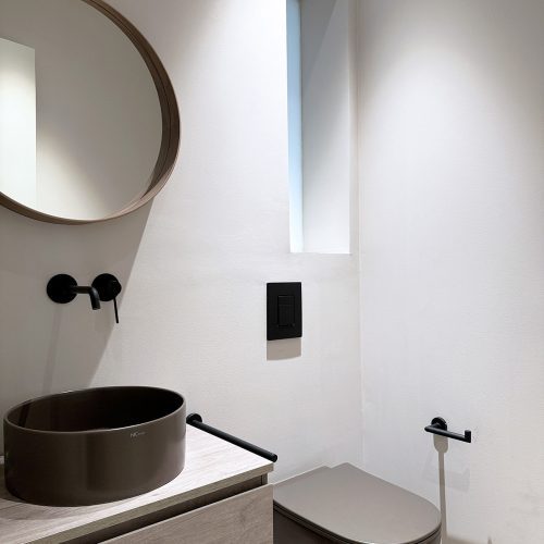 Lavabo suspendido y sanitario en baño auxiliar tras reforma integral de vivienda señorial en el Eixample de Valencia