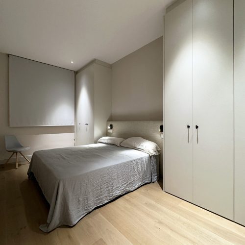 Dormitorio principal con iluminación puntual, armarios integrados y cabecero textil en proyecto de diseño arquitectónico en vivienda de Valencia