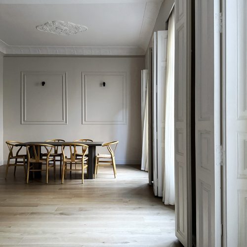 Comedor con rosetón, molduras y ventanales restaurados en uno de los proyectos de arquitectura moderna en Valencia desarrollado por Alfaro Arquitectos