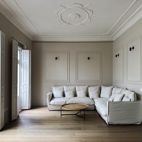 Salón con ventanales restaurados, molduras de escayola y sofá contemporáneo en proyecto de arquitectos de prestigio en Valencia