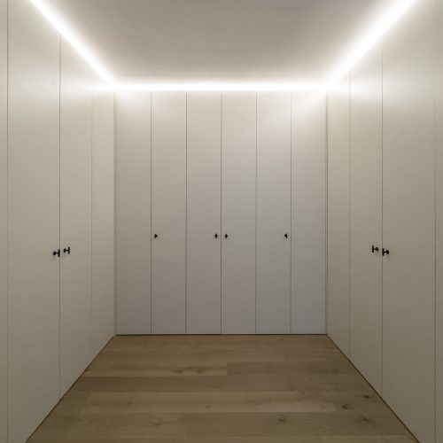 Vestidor con armarios empotrados perimetrales y luz indirecta en techo, resuelto con criterios de arquitectura de interiores en vivienda reformada en Valencia
