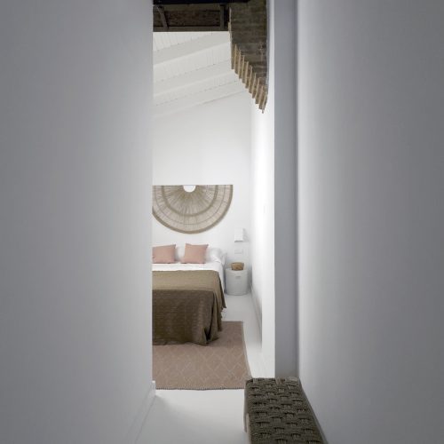 Apertura estructural sobre dormitorio con forjado original de ladrillo y madera expuesto tras reforma integral en vivienda histórica