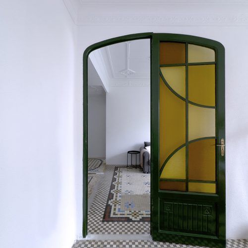 Paso entre estancias con puerta de vidriera original restaurada, mosaico de noya y molduras, obra de arquitecto en Valencia en vivienda del Mercat