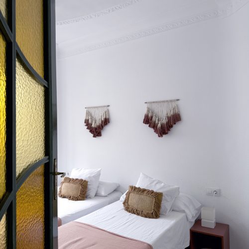 Dormitorio doble con pavimento original, molduras en techo y puerta de vidrieras en proyecto de arquitectura residencial