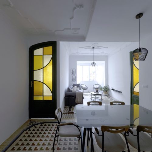 Eje visual entre comedor y salón estructurado mediante diseño arquitectónico con puertas vidriadas y mosaico hidráulico restaurado en vivienda del Mercat
