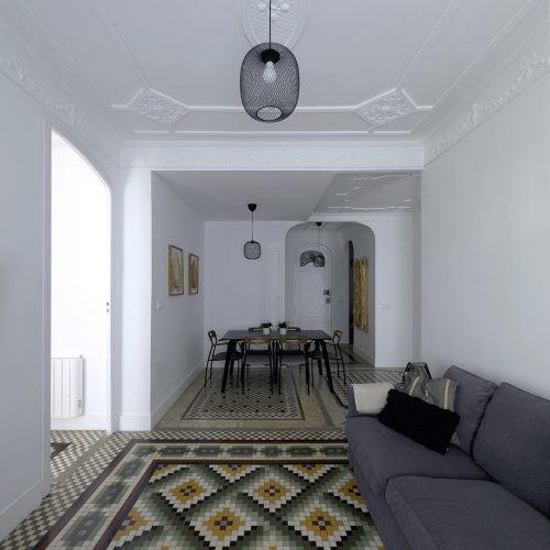 Comedor y salón conectados mediante mosaico hidráulico original y molduras restauradas en intervención de arquitectura residencial en Valencia