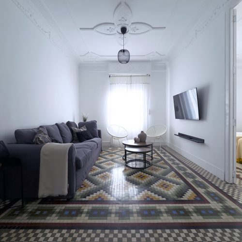 Salón con pavimento hidráulico de noya original y conexión visual hacia dormitorio, intervención de interiorismo residencial en Ciutat Vella