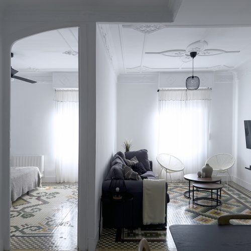 Distribución entre salón y dormitorio conectados por pavimento hidráulico continuo y molduras en techo, solución de diseño arquitectónico en El Mercat