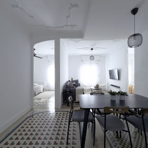 Distribución abierta entre comedor, salón y dormitorios organizada mediante diseño de viviendas con pavimento hidráulico y techos moldurados en El Mercat