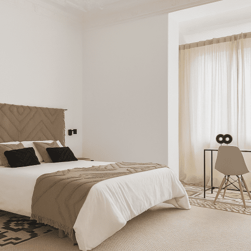 Dormitorio principal con cabecero textil geométrico y escritorio metálico, reformado por mejores arquitectos en Valencia.
