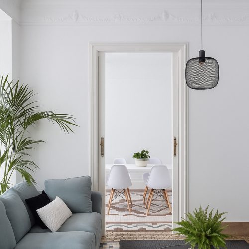 Vista desde salón hacia comedor con mesa blanca y sillas de madera, resultado de una reforma integral de piso en Valencia con estilo contemporáneo.
